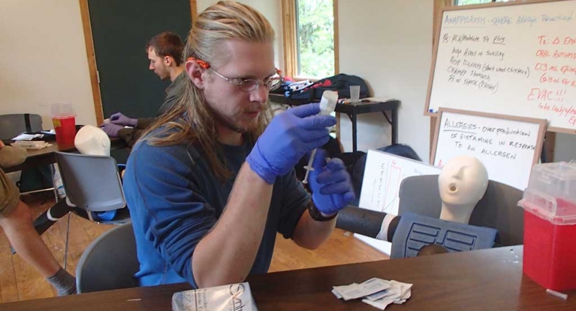 A person fills a syringe during a wilderness first aid class